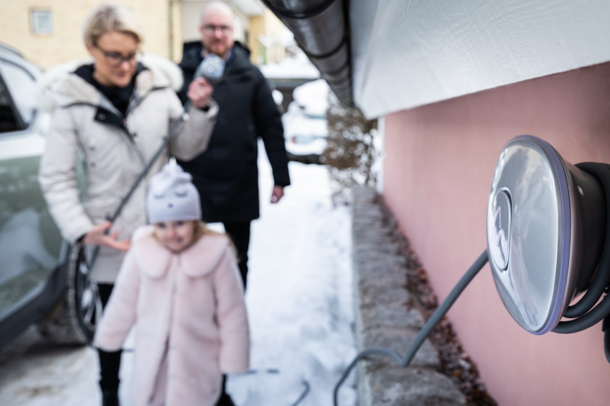 Man, woman and girl infront of their electric car